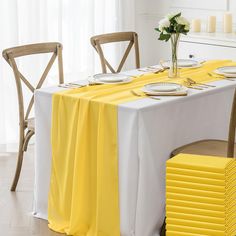 the table is set with yellow and white plates, napkins, and flowers on it