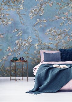 a bedroom with blue wallpaper and pink bedding, along with a gold side table