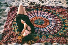 a woman laying on top of a colorful blanket