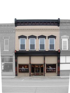 an empty street in front of two buildings with storefronts on each side and windows above them