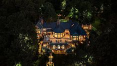 an aerial view of a large house in the woods at night with its lights on