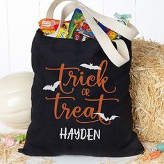 a trick or treat bag sitting on top of hay next to a pile of candy