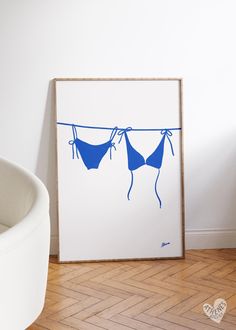 two bikinis hanging on a clothes line in front of a white wall and wooden floor