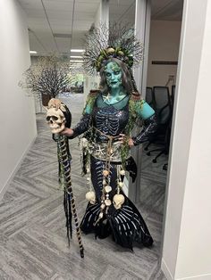 a woman in costume holding two skeleton heads and standing next to each other on a hallway