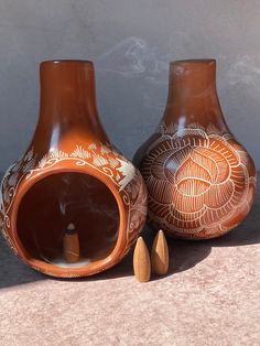 two brown vases sitting next to each other with designs on the outside and inside