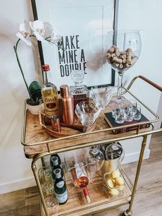 a bar cart with wine glasses and bottles on it