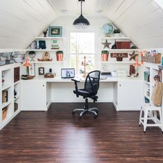 a home office with white shelving and wooden flooring in an atticed room