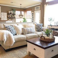 a living room filled with lots of furniture and pillows on top of a table in front of a window