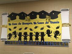 a bulletin board with graduation caps and silhouettes hanging from it's sides in a hallway