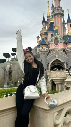 a woman posing for a photo in front of a castle with her hand on the wall