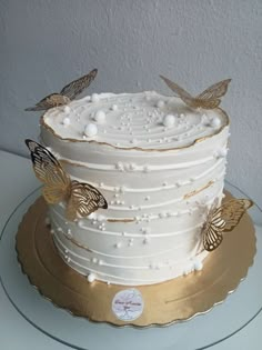 there is a white cake with gold butterflies on it