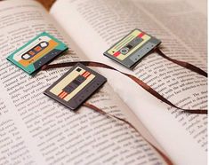 some cassette tapes are laying on top of an open book, with a brown ribbon around them