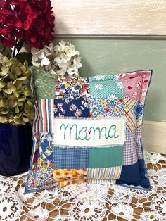 a close up of a pillow on a lace table cloth with flowers in the background