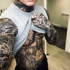 a woman with tattoos on her stomach and arm is posing for the camera in front of a mirror