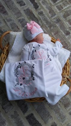 a baby doll laying in a basket on the ground