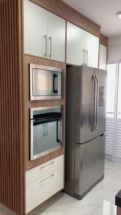 a stainless steel refrigerator freezer sitting next to a wall mounted oven in a kitchen