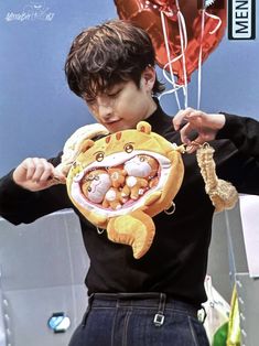 a young boy holding up a stuffed animal in front of a balloon shaped like a tiger