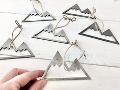 someone is holding some metal triangles on a white wooden table with string and twine