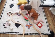 a toddler playing with a train set on the floor