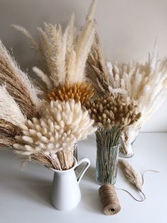 two vases filled with dried grass and twine