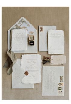 the wedding stationery is laid out on top of each other, including an envelope and ring