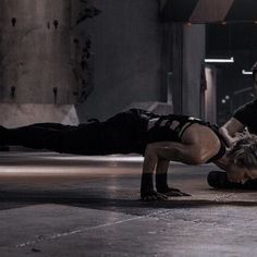 two people are performing an acrobatic move on the floor in a warehouse