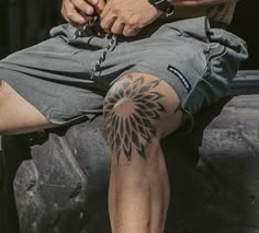 a man sitting on top of a car with tattoos on his legs