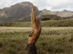 a woman reaching up into the air to catch a frisbee in her hand