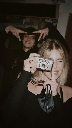 a woman taking a selfie with a camera in front of two men standing behind her