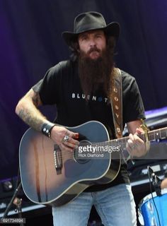 a man with long hair and beard playing an acoustic guitar on stage at a concert