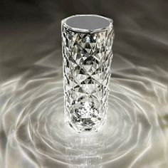 a crystal vase sitting on top of a white surface with water swirling around the base