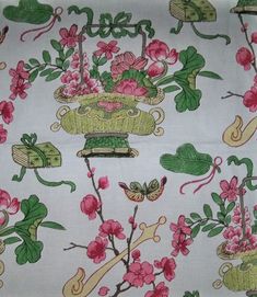 a white fabric with pink flowers and green leaves on the bottom, along with other floral designs