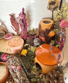 an assortment of clay pots and plants in a display case with fake flowers on the ground