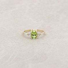 a ring with a green stone and two white diamonds on the side, set in yellow gold