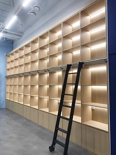 an empty room with shelves and a ladder in the foreground that is lit by lights