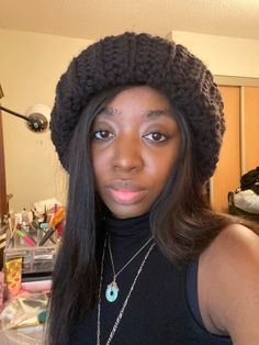 a woman with long hair wearing a black top and a knitted beanie hat