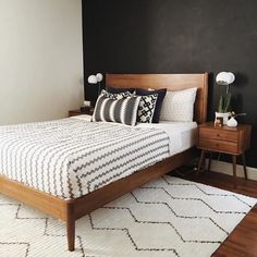 a bedroom with black walls and white rugs on the floor, bedding is neatly made