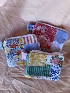 four small purses sitting on top of a bed