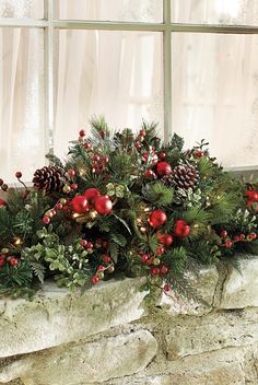 a window sill decorated with evergreen, berries and pineconis in front of a brick wall