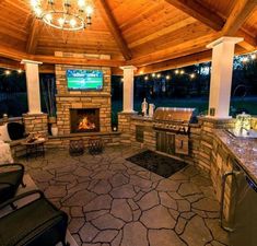 an outdoor living area with grill, television and seating areas in the evening time at dusk