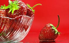 a glass bowl filled with strawberries on top of a table