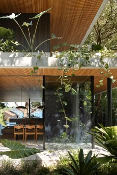 the inside of a house that is surrounded by greenery and trees, with an outdoor dining area in the foreground