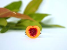 a ring with a piece of fruit on it sitting next to some green leafy plants