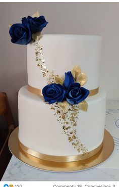 a white and gold wedding cake with blue roses