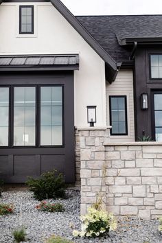 a white and black house with flowers in the front yard