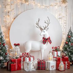 a christmas scene with presents and a deer statue in front of a white wall decorated with lights