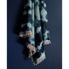 two blue and black towels hanging from a hook on a wall in front of a dark background