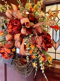 a wreath with orange and red flowers hanging from the front door