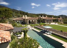 an aerial view of a house with a pool in the foreground and landscaping around it