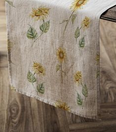 a table runner with sunflowers and leaves printed on it, sitting on a wooden surface